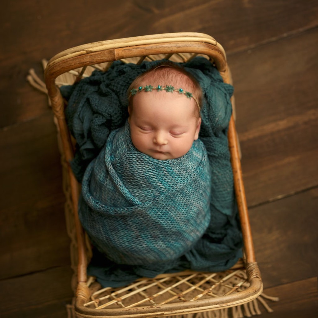 The rattan little bed is perfect for this pretty baby girl in a custom knit teal wrap and headband.