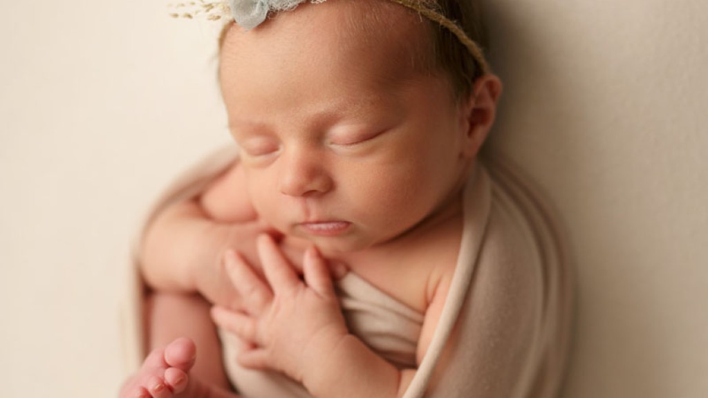 Sweet baby girl wrapped in a cream wrap with her hands folded. Affordable San Diego newborn photography in San marcos, ca. Carlsbad newborn photographer Shelly Rosen took this image in her San Marcos newborn studio.